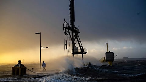A person walks along the banks of the Weser estuary during a storm surge and waves in Bremerhaven, Germany, Friday 22 Dec 2023