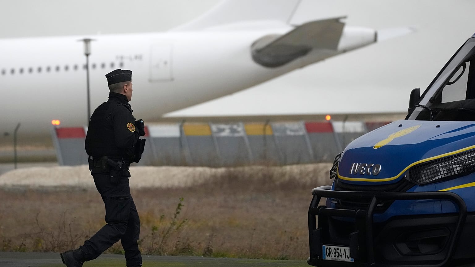Un gendarme marche devant l'avion qui aurait transporté quelque 300 citoyens indiens, à l'aéroport de Vatry, dans l'est de la France, samedi 23 décembre 2023.