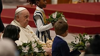 Папа римский Франциск держит статую младенца Иисуса во время рождественской мессы в соборе Святого Петра в Ватикане.