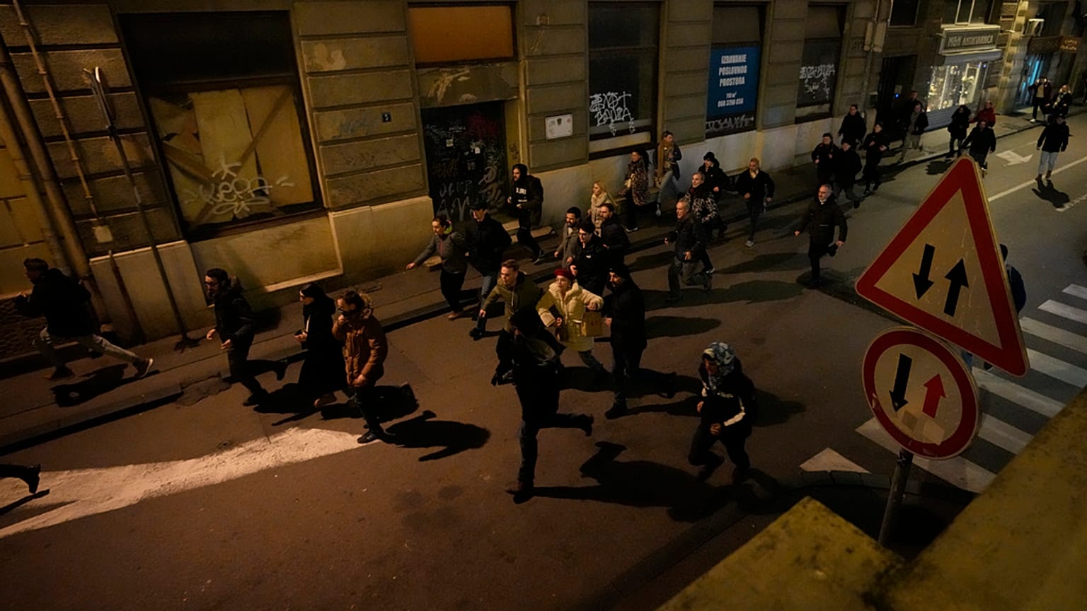 Protesters run away from anti-riot police in Belgrade, Serbia, Sunday, Dec. 24, 2023.