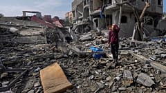 Palestinianos inspeccionam os escombros de um edifício destruído por um ataque israelita no campo de refugiados de Maghazi, no centro da Faixa de Gaza