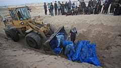 Buldózer rakodja ki a Gázai övezet északi részén megölt és az izraeli hadsereg által átadott palesztinok holttestét egy rafahi tömeges temetésen.