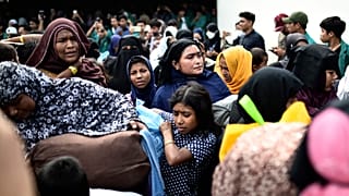 نساء وأطفال من أقلية الروهينغا يحملون ممتلكاتهم في أثناء نقلهم من مأواهم المؤقت في قاعة تابعة للبلدية بعد احتجاج عدد من الطلاب الإندونيسيين ضدهم في باندا آتشيه