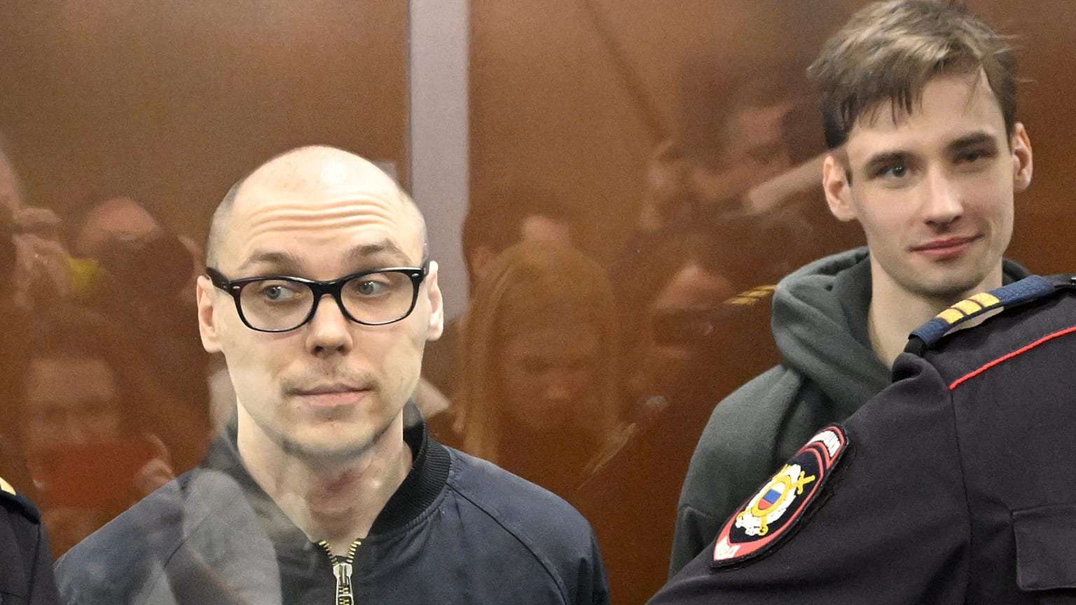 Les poètes russes Artyom Kamardin (G) et Yegor Shtovba (D) se tiennent à l'intérieur de la cage de verre des accusés lors de l'annonce du verdict au tribunal de Moscou le 28 décembre 2023.