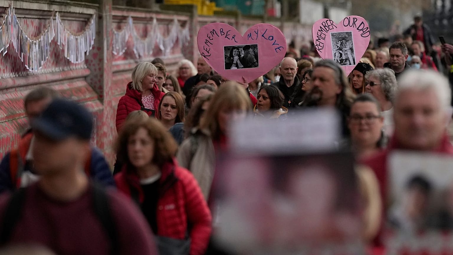 Familiares de fallecidos por COVID caminan junto al muro conmemorativo nacional de Covid en Londres, el martes 29 de marzo de 2022.