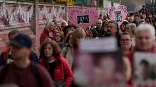 Familiares de fallecidos por COVID caminan junto al muro conmemorativo nacional de Covid en Londres, el martes 29 de marzo de 2022.