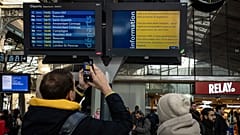 Ein Passagier fotografiert auf dem Pariser Bahnhof Gare du Nord eine Informationstafel mit gestrichenen Eurostar-Zügen, 30. Dezember 2023.