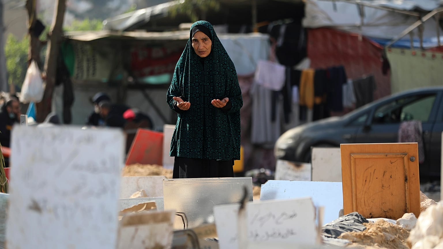 امرأة فلسطينية تقرأ الفاتحة في مقبرة جماعية بساحة مستشفى الشفاء في غزة