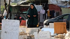 امرأة فلسطينية تقرأ الفاتحة في مقبرة جماعية بساحة مستشفى الشفاء في غزة