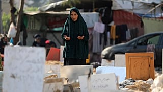 امرأة فلسطينية تقرأ الفاتحة في مقبرة جماعية بساحة مستشفى الشفاء في غزة