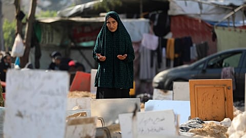 امرأة فلسطينية تقرأ الفاتحة في مقبرة جماعية بساحة مستشفى الشفاء في غزة