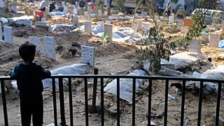 Bir zamanlar Gazze'nin en büyük hastanesi olan ancak İsrail saldırılarında harabeye dönen Şifa Hastanesi'nin bahçesinde gömülen kişilerin mezarlarına bakan Filistinli çocuk