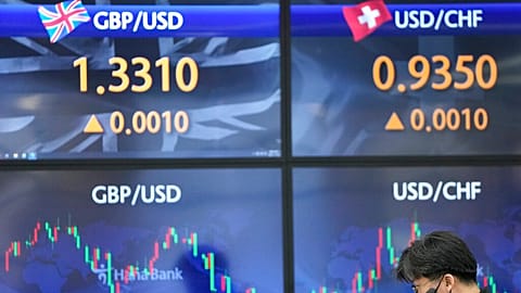 A currency trader talks near the screens showing the foreign exchange rates at a foreign exchange dealing room in Seoul, South Korea, Friday, Nov. 26, 2021. Asian stock market