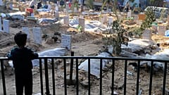 طفل فلسطيني ينظر إلى قبور شهداء القصف الإسرائيلي على القطاع والمدفونين داخل أرض مستشفى الشفاء في مدينة غزة. 2024/01/02