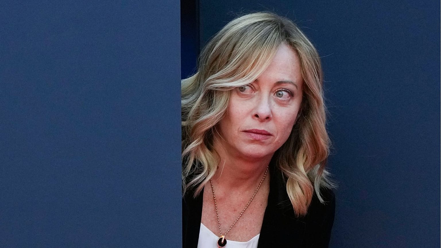 Italy's Prime Minister Giorgia Meloni peers out from a door before introducing Britain's Prime Minister Rishi Sunak at the annual political festival Atreju in December 2023.