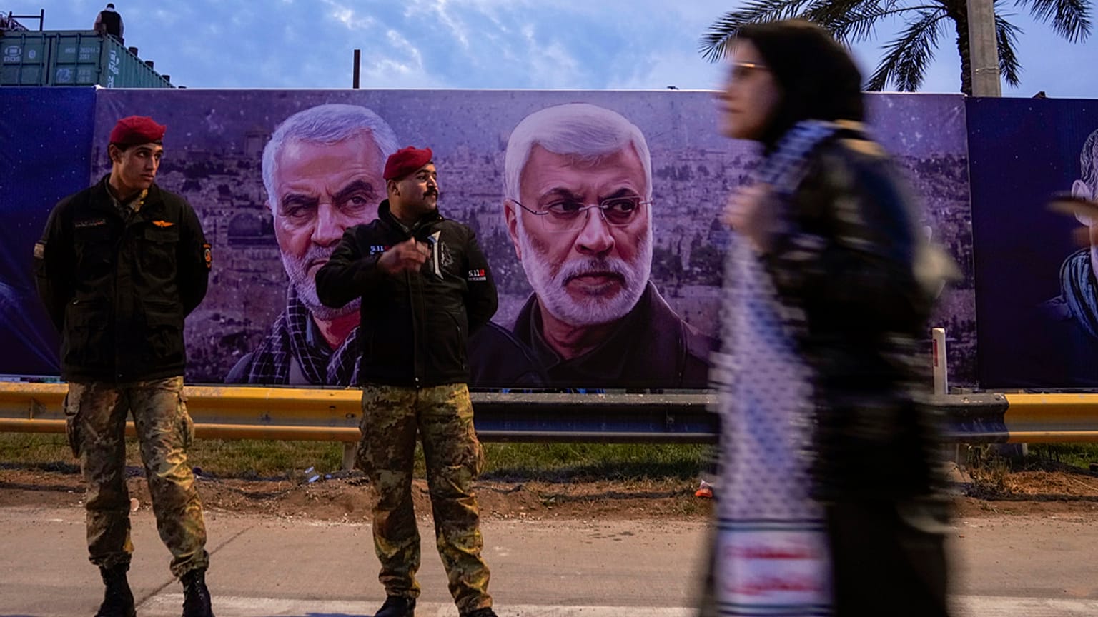 امرأة تحمل لافتة تظهر الجنرال قاسم سليماني، قائد فيلق القدس الإيراني، وأبو مهدي المهندس، نائب قائد الحشد الشعبي، خلال الذكرى الرابعة لاغتيالهما في بغداد، العراق