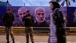 امرأة تحمل لافتة تظهر الجنرال قاسم سليماني، قائد فيلق القدس الإيراني، وأبو مهدي المهندس، نائب قائد الحشد الشعبي، خلال الذكرى الرابعة لاغتيالهما في بغداد، العراق