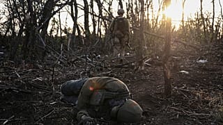 O comandante da unidade de assalto da 3ª Brigada de Assalto, conhecido pelo indicativo de chamada "Fedia", passa pelo corpo de um soldado russo morto.