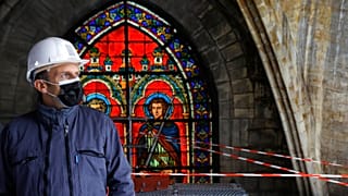 French President Emmanuel Macron stands by a stained glass at the reconstruction site of the Notre-Dame de Paris cathedral on April 15, 2021.