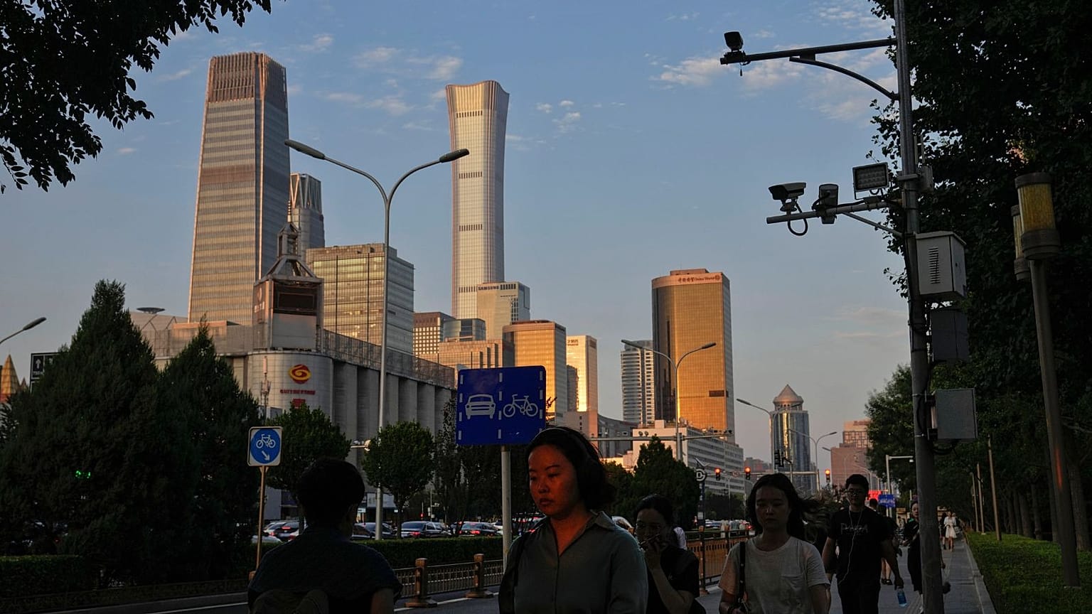 An evening sunlight casts on a woman as people walk near the Central Business District during the rush hour in Beijing on Monday, Aug. 14, 2023.