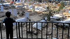  A Palestinian child looks at the graves of people killed in the Israeli bombardment of the Gaza Strip and buried inside the Shifa Hospital grounds in Gaza City on 31 Dec. 