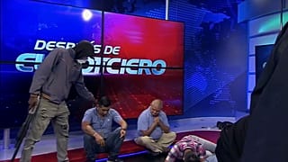 Una persona armada y enmascarada de pie junto a periodistas durante una transmisión en vivo, en Guayaquil, Ecuador, el martes 9 de enero de 2024.
