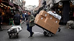 Two men pull trollies with goods in a street market in a commercial district in Istanbul, Turkey, Thursday, Dec. 21, 2023. Turkey's central bank hiked its key interest rate by