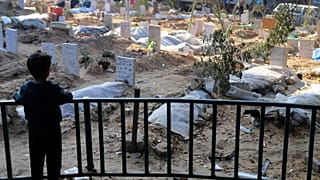 Un niño palestino observa las tumbas de las personas muertas en el bombardeo israelí de la Franja de Gaza y enterradas en el recinto del hospital Shifa de la ciudad de Gaza, 31 de diciembre de 2023.
