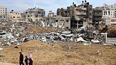 عائلة فلسطينية تسير أمام المباني المدمرة في قطاع غزة.