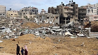 عائلة فلسطينية تسير أمام المباني المدمرة في قطاع غزة.