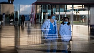 Personas que usan máscaras como medida de precaución caminan dentro de un hospital en Barcelona, España, el lunes 8 de enero de 2024.