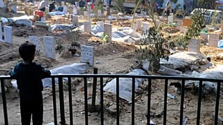 Ένα παλαιστινιακό παιδί κοιτάζει τους τάφους των ανθρώπων που σκοτώθηκαν κατά τους ισραηλινούς βομβαρδισμούς της Λωρίδας της Γάζας και θάφτηκαν μέσα στον χώρο του νοσοκομείου Σίφα στην πόλη της Γάζας τον Δεκέμβριο