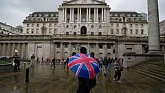 A woman with an umbrella stands in front of the Bank of England, at the financial district in London, Thursday, Nov. 3, 2022. 