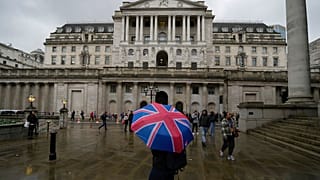 A woman with an umbrella stands in front of the Bank of England, at the financial district in London, Thursday, Nov. 3, 2022. 