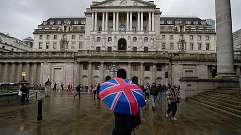 A woman with an umbrella stands in front of the Bank of England, at the financial district in London, Thursday, Nov. 3, 2022. 