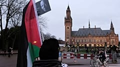 یک طرفدار فلسطینیان در مقابل ساختمان دادگاه در لاهه به تاریخ دوازدهم ژانویه ۲۰۲۴