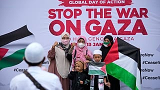 صورة لعائلة على خلفية رسالة تطالب بإنهاء الحرب على غزة خلال مسيرة لدعم الفلسطينيين خارج السفارة الأمريكية في جاكرتا، إندونيسيا، 13 يناير 2024.