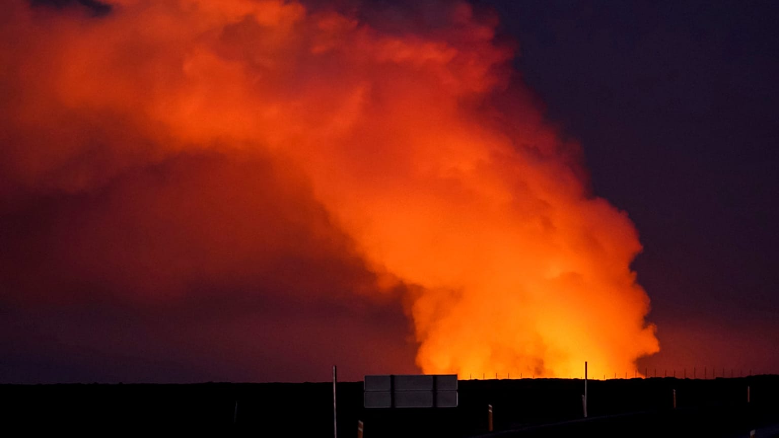 A view of the plume of gas lighted up by the lava from the erupting volcano seen from Suðurstrandavegur, the road that leads to Grindavík, Iceland, Sunday Jan. 14, 2024