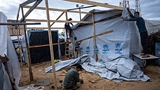 فلسطينيون نازحون بسبب القصف الإسرائيلي لقطاع غزة يصنعون خياماً تحت المطر في خان يونس، 19 نوفمبر 2023.