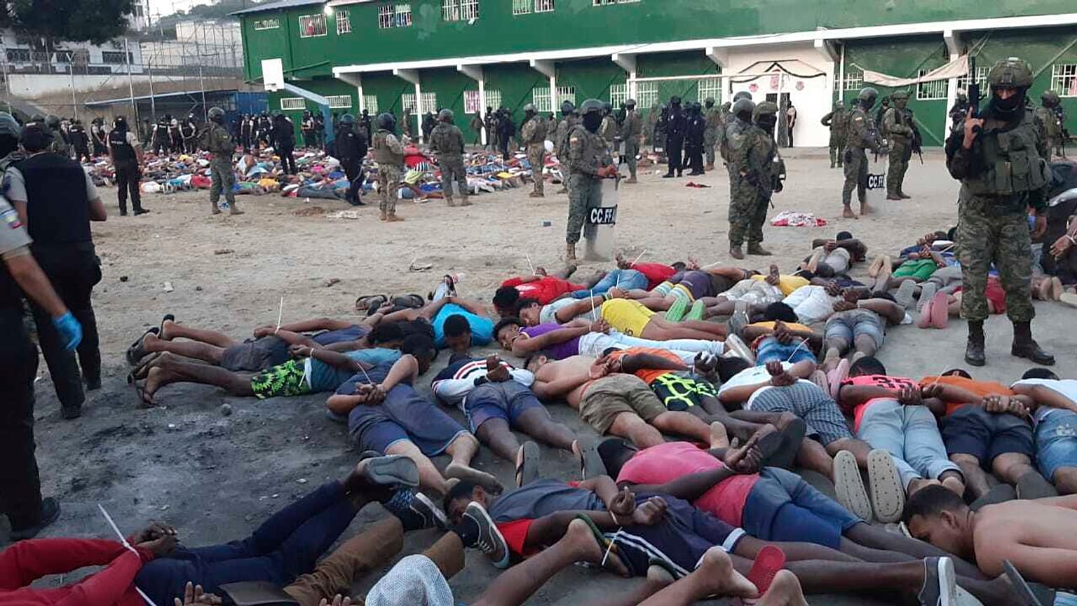 This photo released by Ecuador's Armed Forces shows soldiers standing over prisoners, with their hands tied behind their backs, at the prison in Esmeraldas, Ecuador, Sunday, J