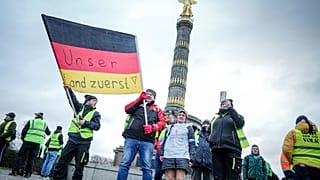Bauern halten eine Fahne mit der Aufschrift "Unser Land zuerst" in die Höhe, während sie vor der Siegessäule in Berlin protestieren, Montag. Jan. 15, 2024.