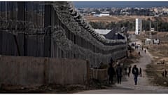 فلسطينيون نزحوا إثر القصف الإسرائيلي على غزة يسيرون بجوار الحدود مع مصر، في رفح الأحد 14 يناير 2024