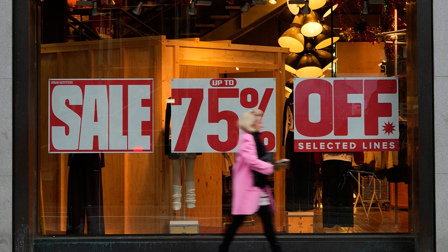 A shopper passes a window displaying a sale sign on Oxford Street in London, Wednesday, Dec. 20, 2023. 
