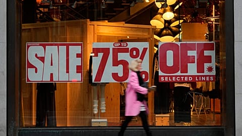 A shopper passes a window displaying a sale sign on Oxford Street in London, Wednesday, Dec. 20, 2023. 