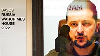 Una mujer observa la pantalla de su teléfono móvil frente a una imagen del presidente de Ucrania, Volodímir Zelenski, en el Foro de Davos.