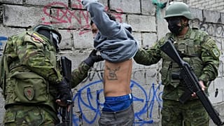Dos soldados detienen brevemente a un joven para comprobar si tiene tatuajes relacionados con pandilleros, mientras patrullan la zona sur de Quito, Ecuador.