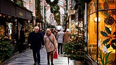 People hold hands as they walk in a Christmas decorated Burlington Arcade, in London, 2023.