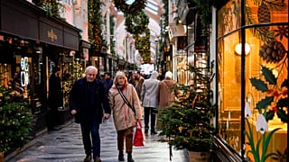 People hold hands as they walk in a Christmas decorated Burlington Arcade, in London, 2023.