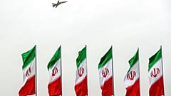 Ein Kampfjet fliegt während einer Militärparade in Teheran über iranischen Flaggen 