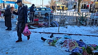 Des personnes passent devant les corps des victimes tuées lors des bombardements qui, selon les autorités russes à Donetsk, ont été menés par les forces ukrainiennes.